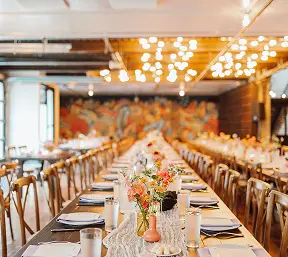 A long dining table set with chairs and adorned with a vase of flowers.