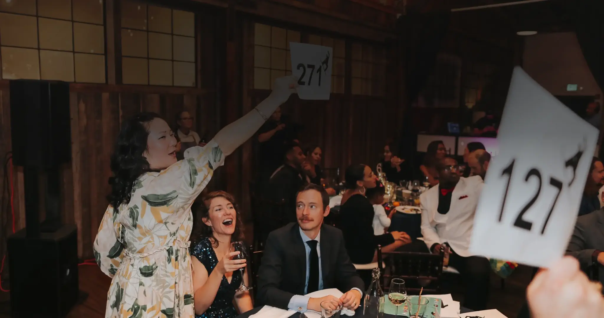 Guests raising bid paddles during the live auction at a nonprofit gala at SoDo Park, Seattle