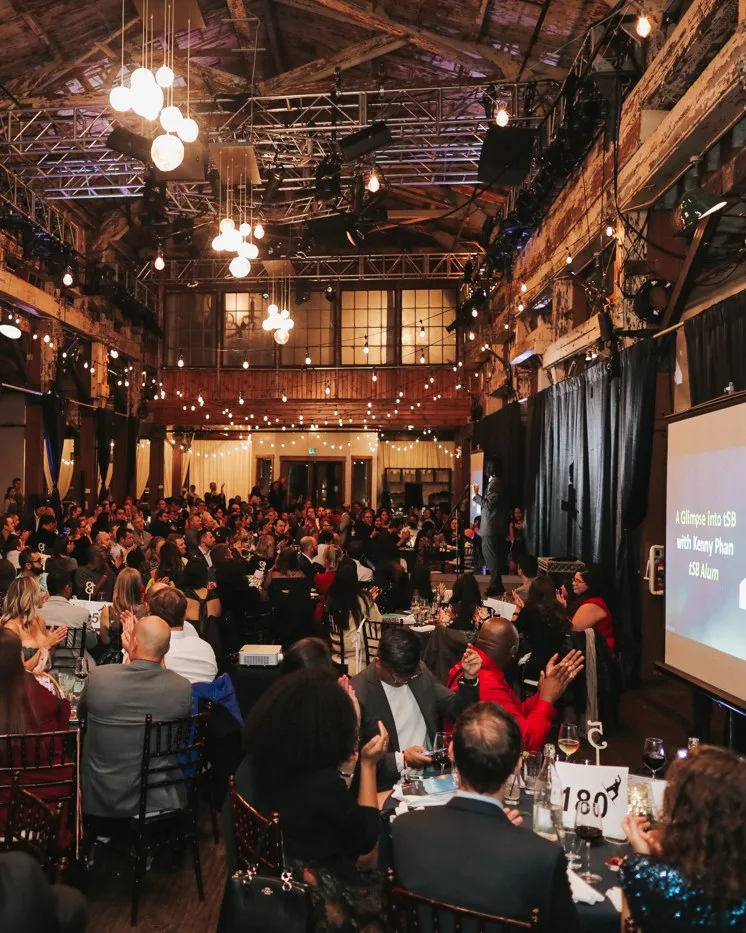 Guests applauding a presentation on screen during a gala dinner at SoDo Park