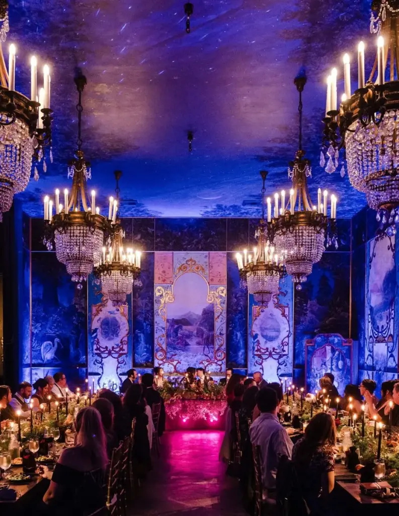 A candlelit gala dinner for a full ballroom of guests beneath crystal chandeliers at The Ruins