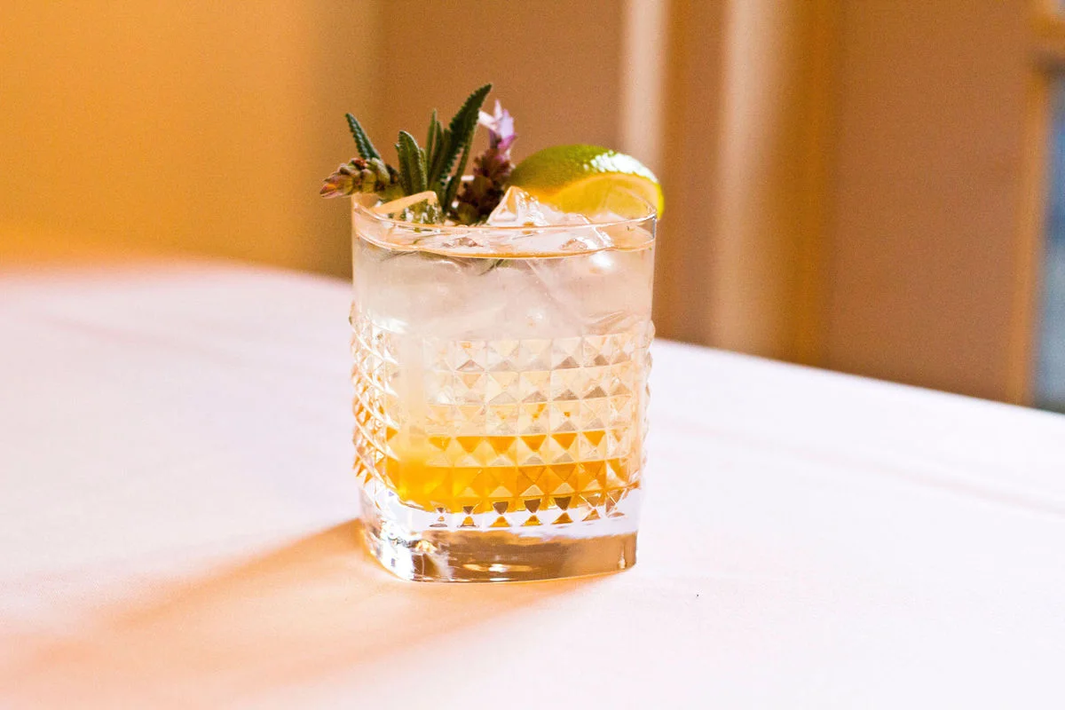 Signature cocktail garnished with rosemary and lime