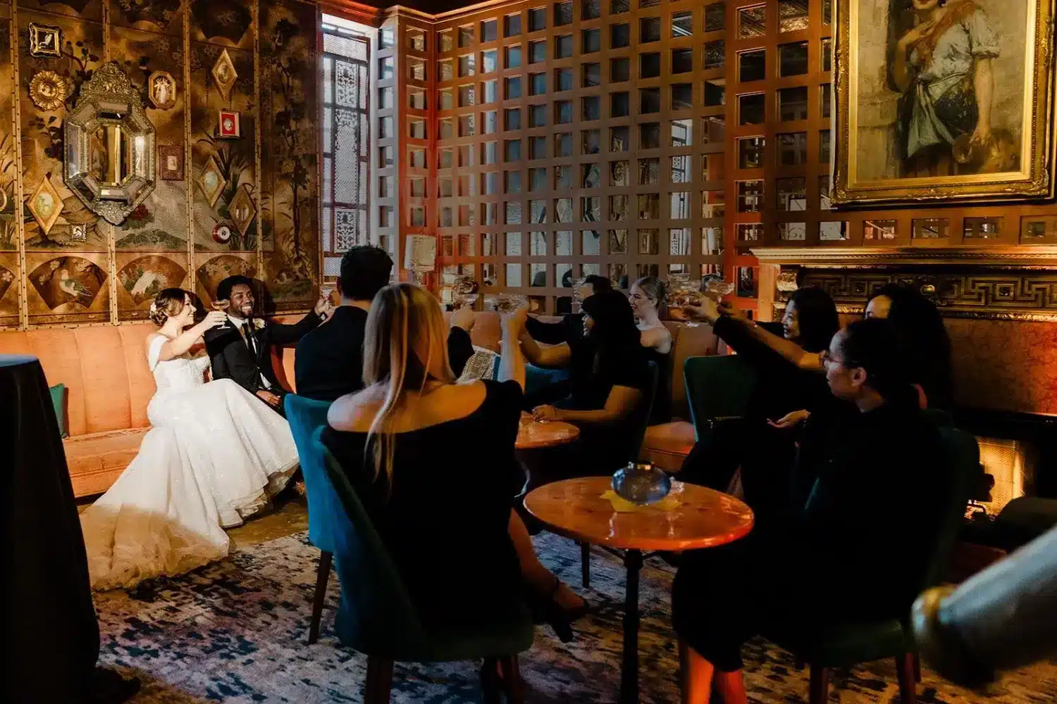 Newlyweds raising a toast with friends around the fireside lounge at The Ruins, an intimate wedding venue in Seattle