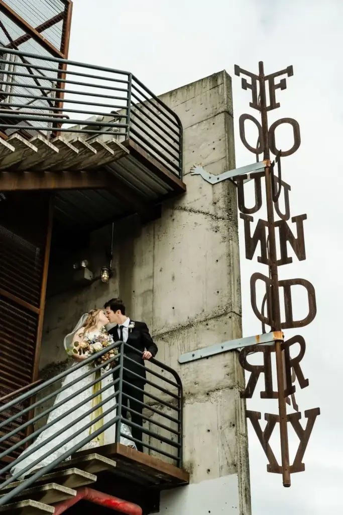 Newlyweds on the steel staircase beside the FOUNDRY letters at Fremont Foundry, a wedding venue in Fremont, Seattle