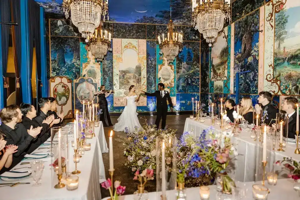 A first dance between candlelit tables of guests in the muraled ballroom at The Ruins, Seattle