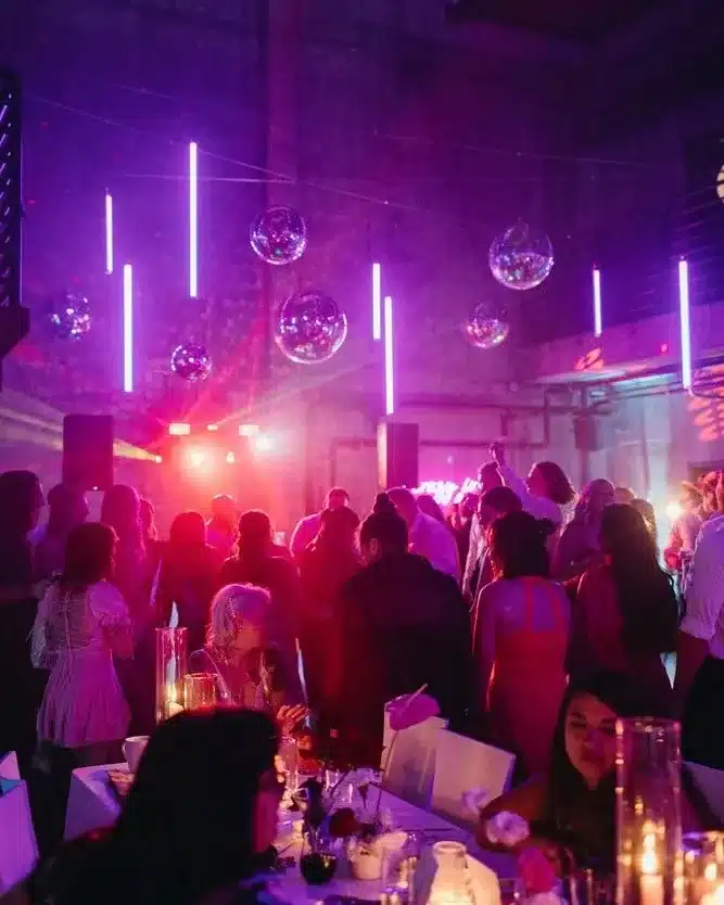A packed dance floor under purple lights and mirror balls at a birthday party at Fremont Foundry