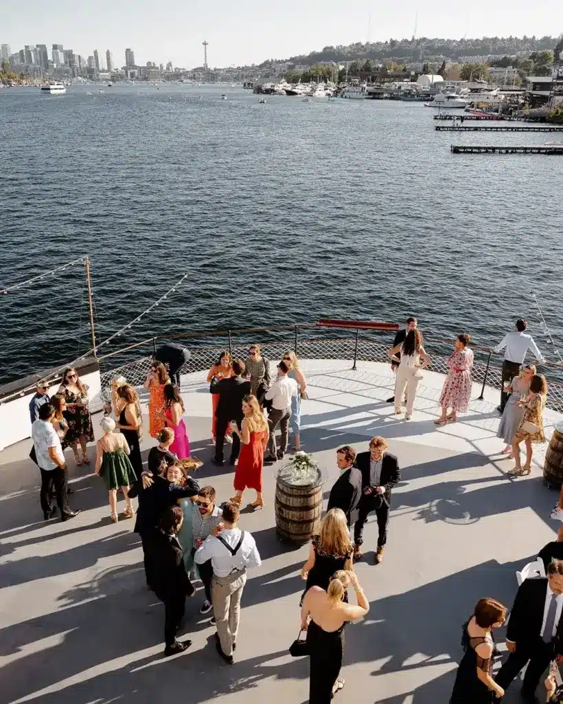 Guests mingling on the deck of the MV Skansonia with Lake Union and the Seattle skyline behind