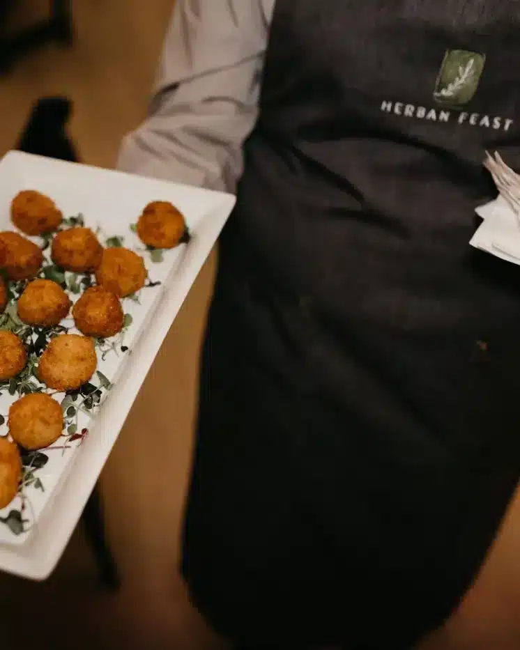 A Herban Feast server carrying a tray of hot appetizers